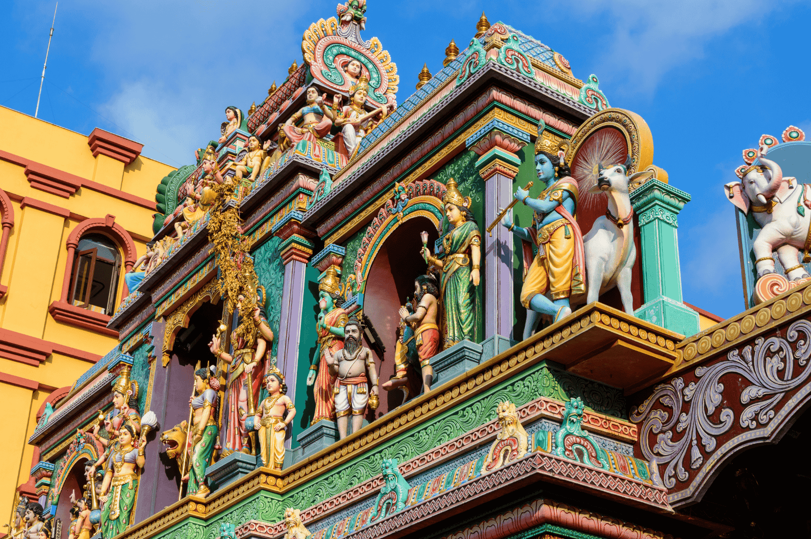 Little-India-Food- (6) Ornate Hindu temple facade in Little India, Singapore—bursting with vividly painted deities, mythological figures, and sacred animals in tiered Dravidian architecture. A spiritual and visual anchor along the Spice Route, where devotion and artistry converge in kaleidoscopic detail.