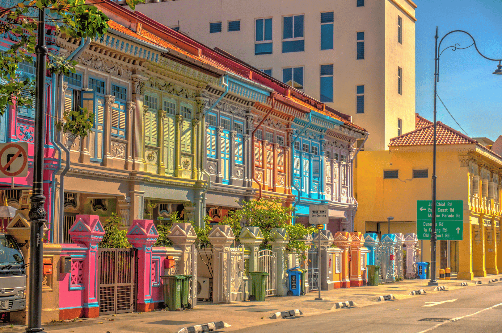 Katong- (1) A pastel-hued row of Peranakan shophouses in Katong, Singapore, bursts with architectural charm—ornate wooden shutters, tiled roofs, and decorative moldings echoing colonial and local styles—setting a vibrant stage for the district’s rich street food culture.