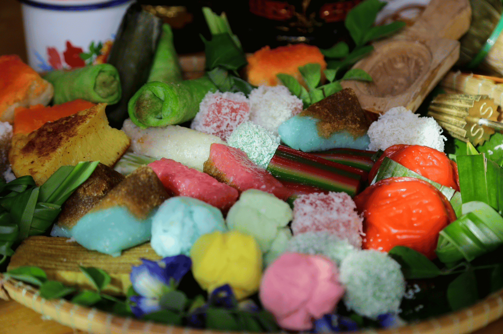 Katong- (4) A woven tray of Peranakan kueh—onde-onde, kueh lapis, and banana-leaf-wrapped sweets—showcases Katong’s street food pleasure principle in vibrant, coconut-laced color.