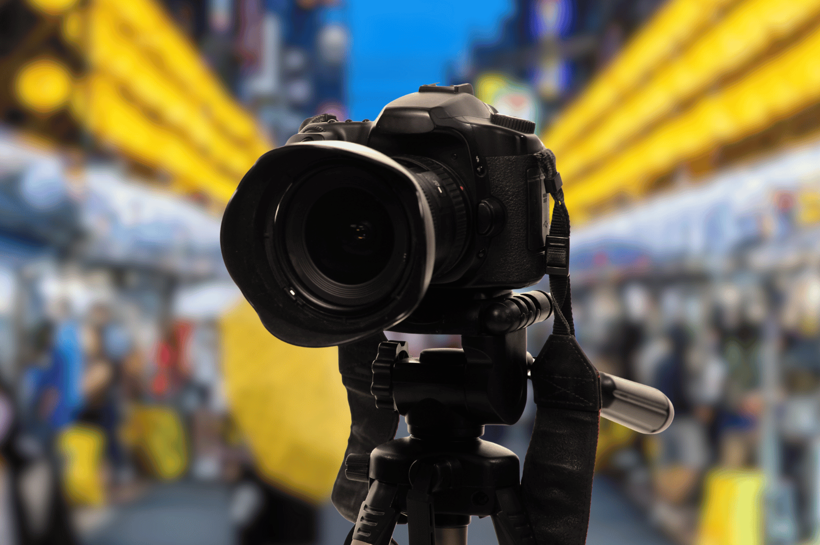 Night-market-Pics- (3) A professional DSLR camera stands poised on a tripod amid a glowing urban market, its lens aimed at the blur of golden lights and bustling silhouettes—capturing the pulse of street life through the seductive lens of low-light food photography.