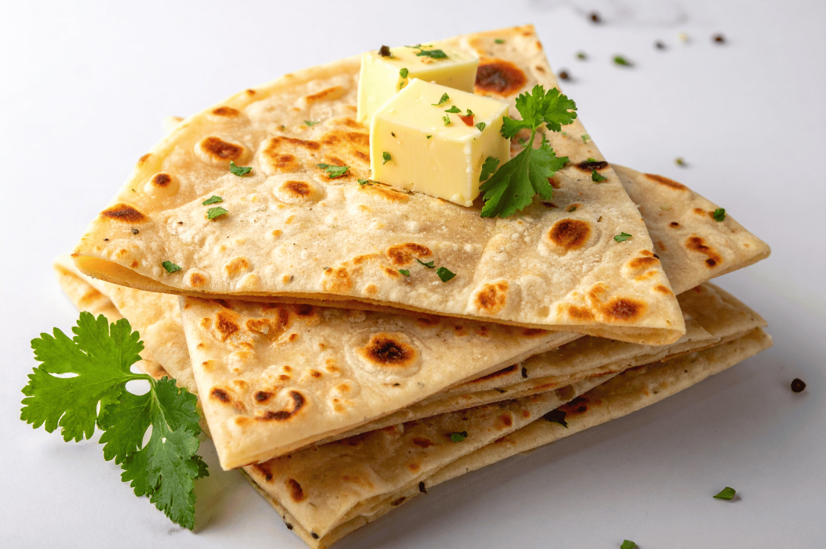 Golden parathas stacked high, butter melting into their crisp folds, garnished with cilantro—an irresistible prelude to Singapore’s roti prata seduction.