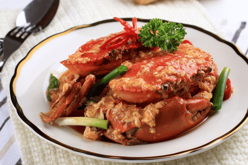 Chili-Crab- (2) An elegant presentation of chili crab on a gold-rimmed plate, smothered in a creamy, egg-streaked sauce and garnished with curly parsley, scallions, and thin red chili ribbons.