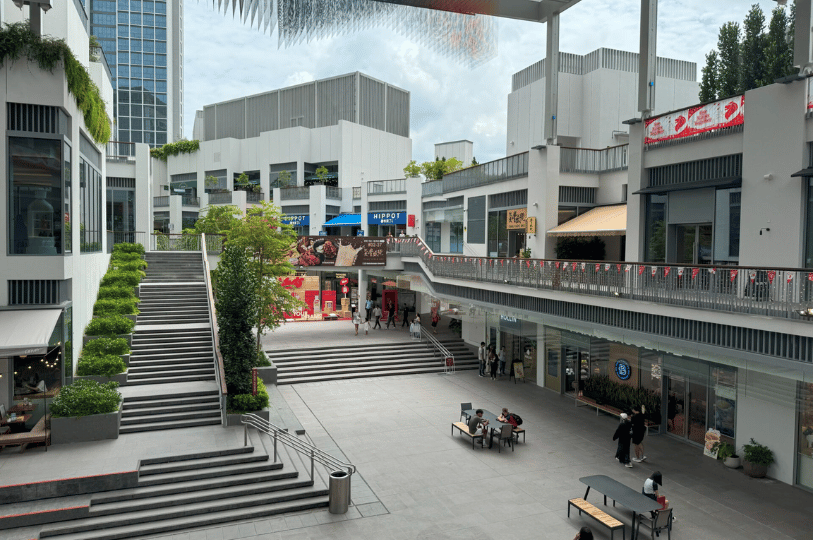 Holland-Village- (5) The spacious, minimalist plaza of One Holland Village, showing the clean architectural lines of the shopping complex and wide stone steps leading to retail shops.