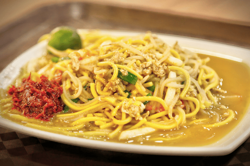 Tiong-Bahru- (4) A vibrant plate of Hokkien Mee, showing a mix of yellow noodles and thick bee hoon braised in a rich gravy. It is served with a side of red sambal chili and a fresh calamansi lime for acidity.