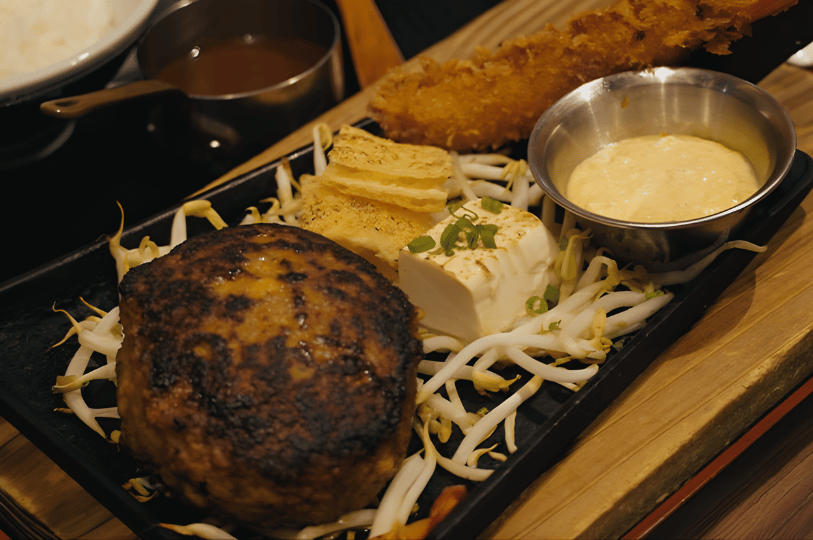 TanjongPagar- (2) A sizzling Japanese Hamburg steak set served on a black iron hot plate with bean sprouts, silken tofu topped with scallions, and a golden fried ebi tempura, reflecting the diverse modern food scene in Hamburg Steak Keisuke, Tanjong Pagar.