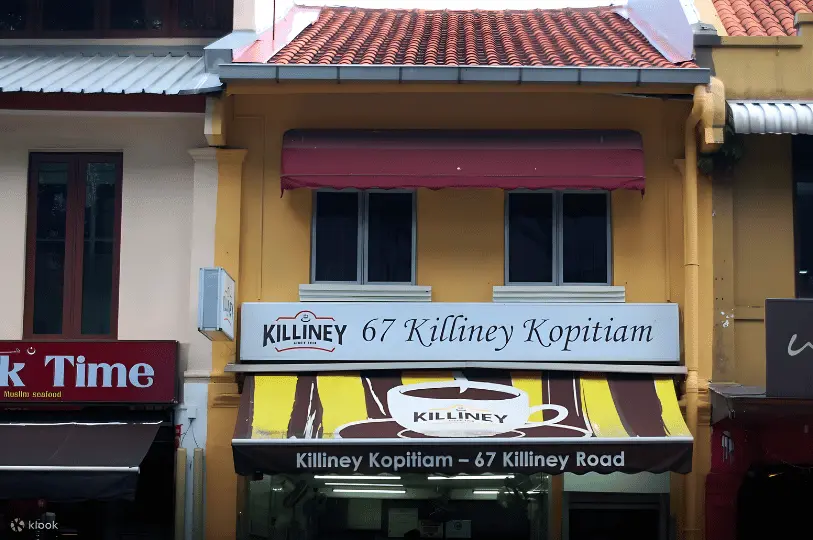 Breakfast-Spots- (5) Exterior architectural shot of 67 Killiney Kopitiam, capturing its classic brown-and-yellow awning and white signage bathed in soft daylight against a traditional yellow shophouse facade.
