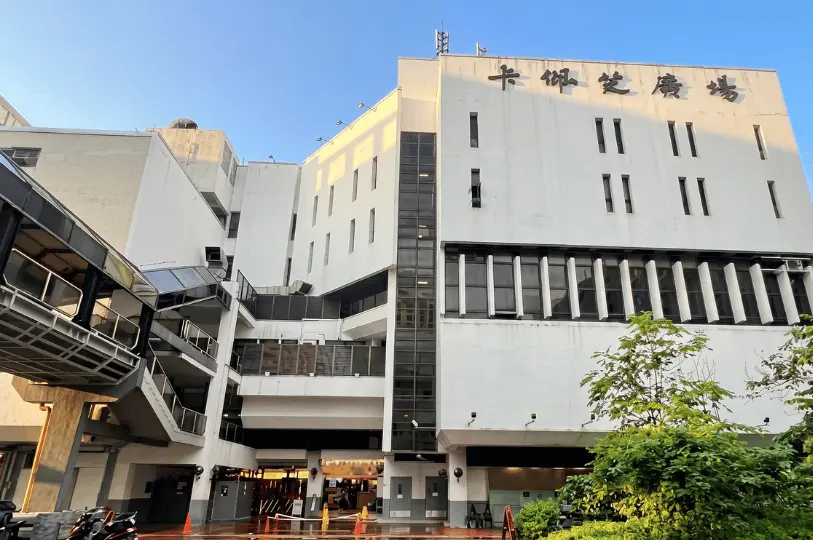 Exterior view of the Cuppage Plaza building against a clear blue sky, featuring its stark white facade, geometric architecture, and dark Chinese characters near the roofline.