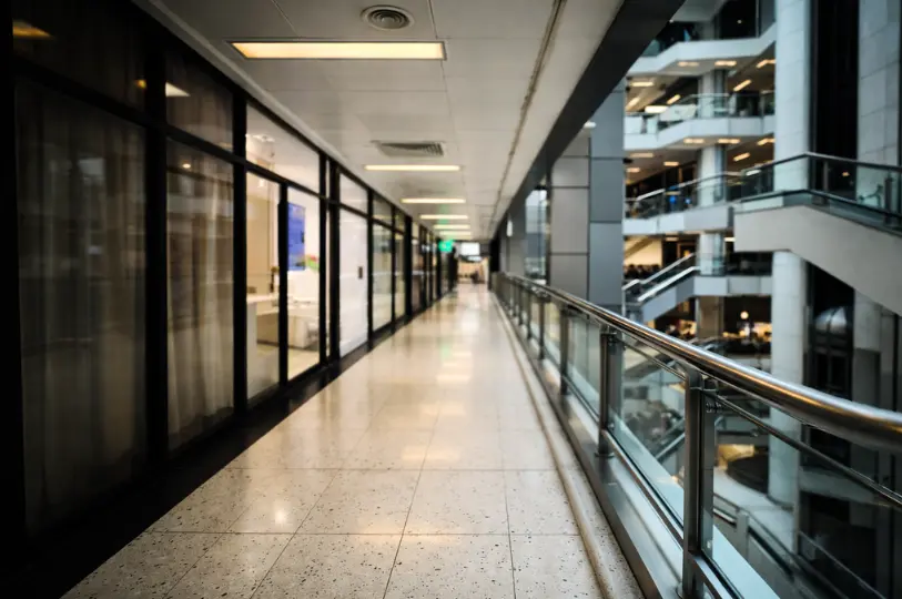 A quiet hallway inside Cuppage Plaza, featuring a tiled walkway, glass-fronted shops, and a view of the multi-level architecture.
